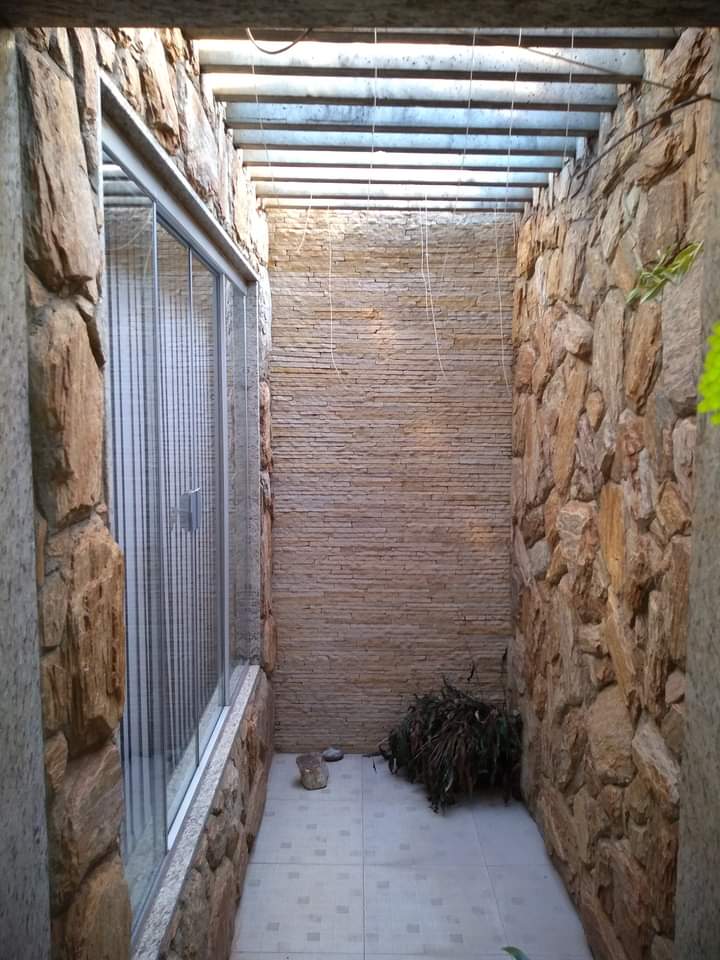Corredor externo com paredes de pedra natural e tijolinho